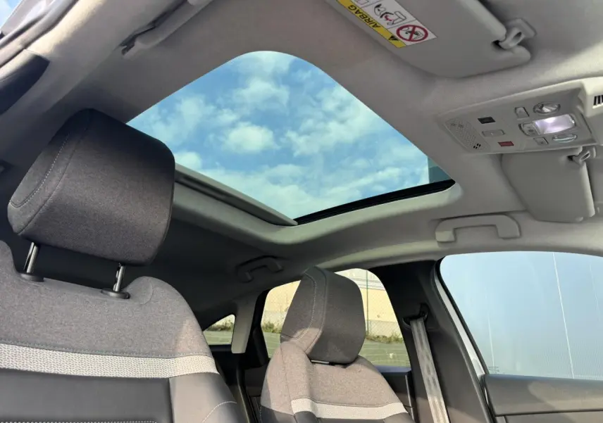 Vue intérieure avant droite de la Citroën C4 2024 avec toit ouvrant électrique et sièges tissu gris chiné.