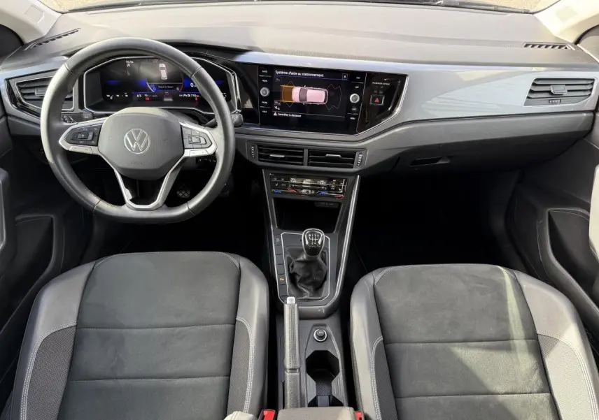 Vue intérieure frontale du tableau de bord et des sièges sport noirs de la Volkswagen Polo 1.0 TSI 2025 avec boîte manuelle.
