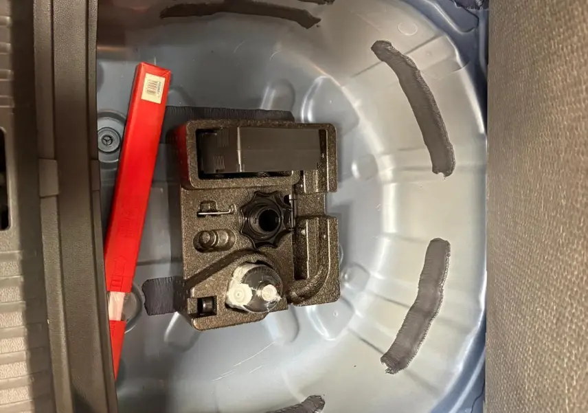 Vue rapprochée de la zone de rangement sous le coffre d’un SEAT Arona bleu saphir, montrant l’emplacement pour roue de secours.