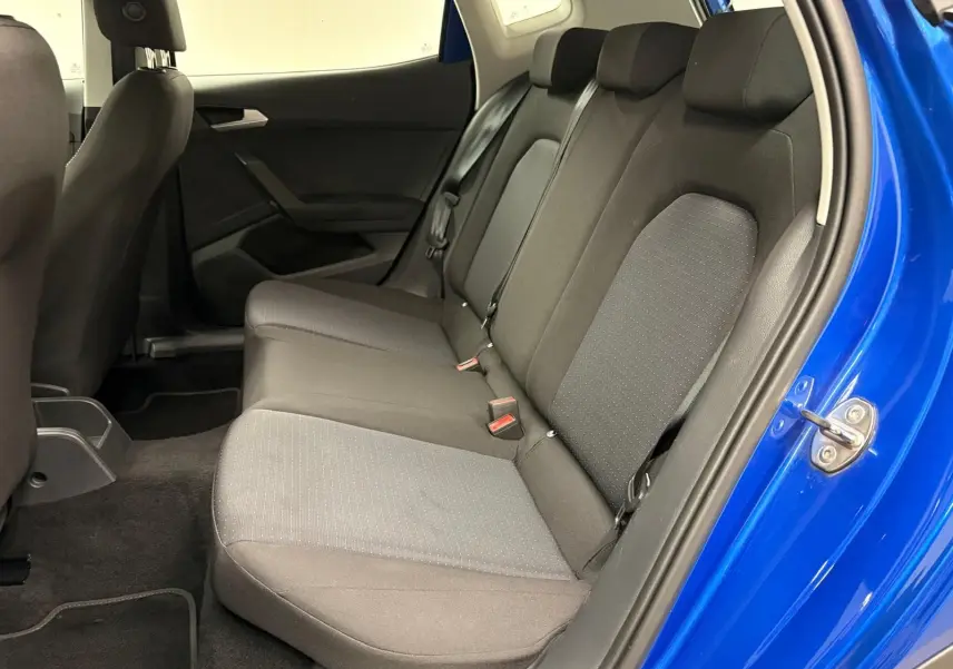 Vue intérieure côté gauche des sièges arrière noirs d’un SEAT Arona 2025 en Bleu Saphir avec porte ouverte.