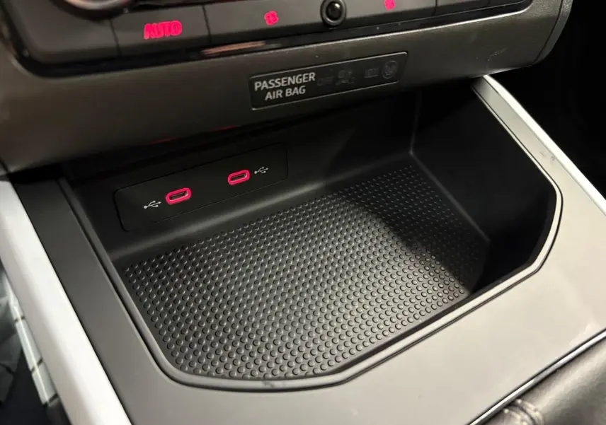 Gros plan sur la console centrale du SEAT Arona 2025, montrant deux ports USB-C avec éclairage rouge et un espace de rangement noir.