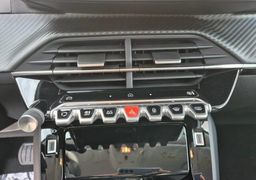 Vue rapprochée du tableau de bord noir brillant de la Peugeot 208 Hybrid 110 e-DCS6 Allure avec commandes climatisation et boutons fonctionnels.