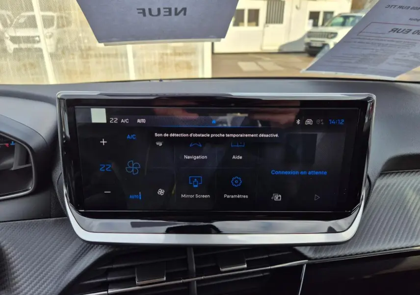 Écran tactile central du tableau de bord de la Peugeot 208 blanc, affichant les options de navigation et climatisation.