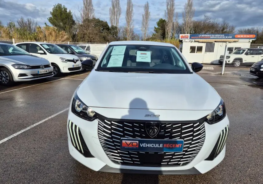 Peugeot 208 Hybrid blanc vue de face, avec calandre noire distinctive et feux LED verticaux allumés.