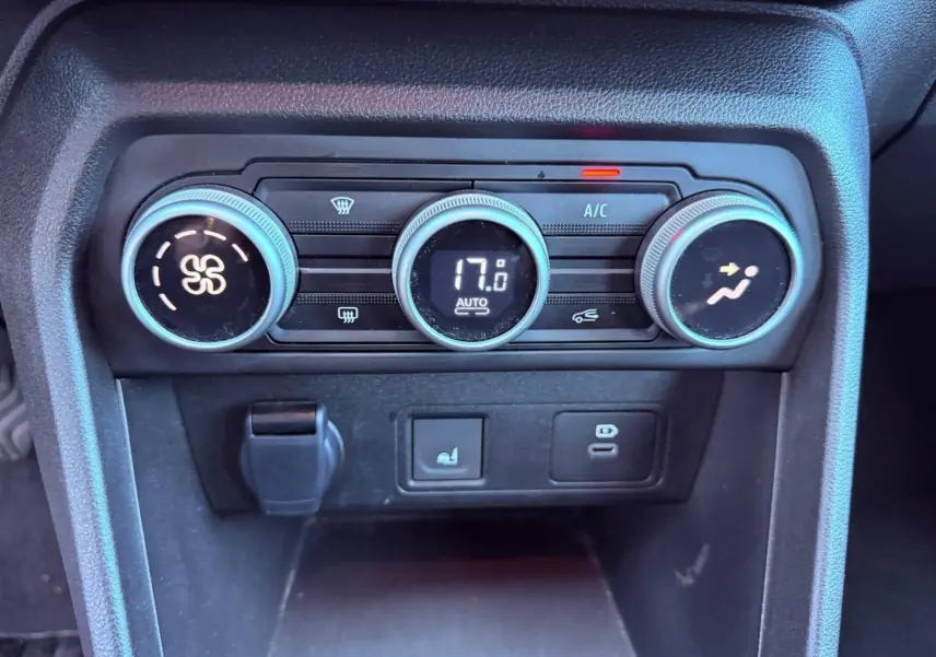 Gros plan sur la console centrale noire avec commandes de climatisation automatique affichant 17°C dans une Dacia Sandero Kaki Lichen.