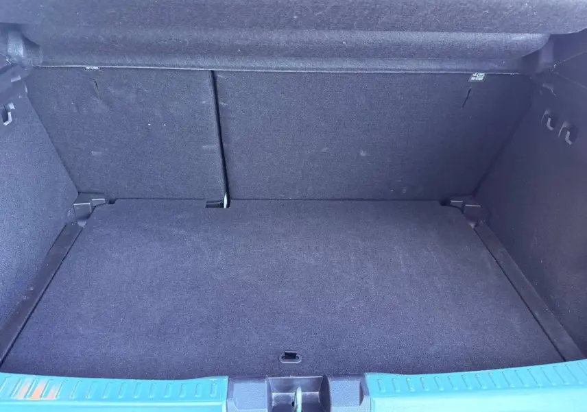 Coffre spacieux vu de face, revêtement intérieur noir, seuil de chargement en plastique gris.