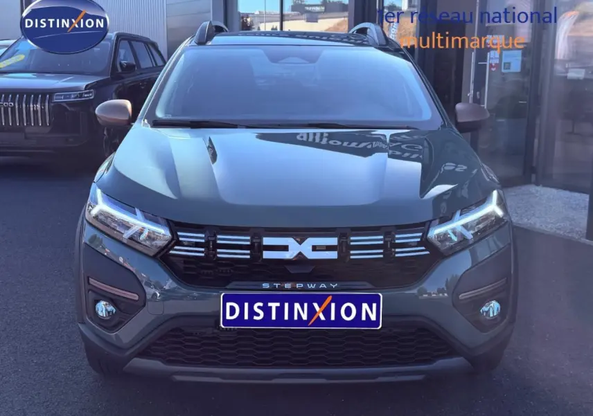 Vue avant d'une Dacia Sandero Stepway 2025 en kaki lichen avec calandre noire et phares LED allumés.