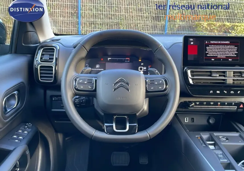 Vue intérieure centrée sur le volant et tableau de bord du Citroën C5 Aircross 2025 en cuir noir avec écran tactile.