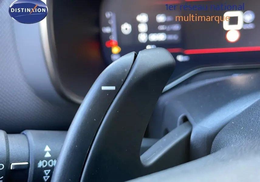 Gros plan sur la palette de changement de vitesse côté droit du volant du Citroën C5 Aircross noir perla metal, tableau de bord flou en arrière-plan.