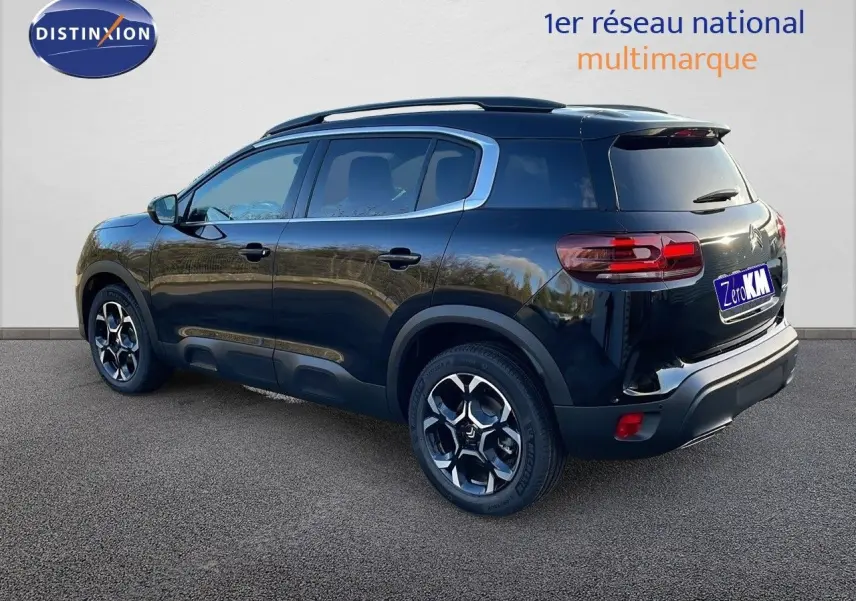 Vue 3/4 arrière droite d'un Citroën C5 Aircross noir Perla Metal avec jantes bi-ton et barres de toit visibles.