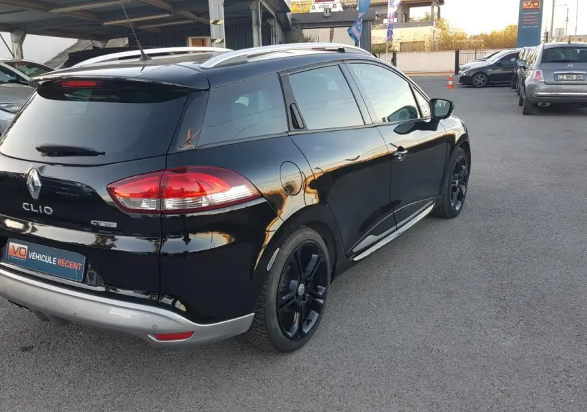 Renault Clio IV Estate TCe 120 GT EDC noir vue 3/4 arrière droit avec jantes alliage noires et vitres surteintées.