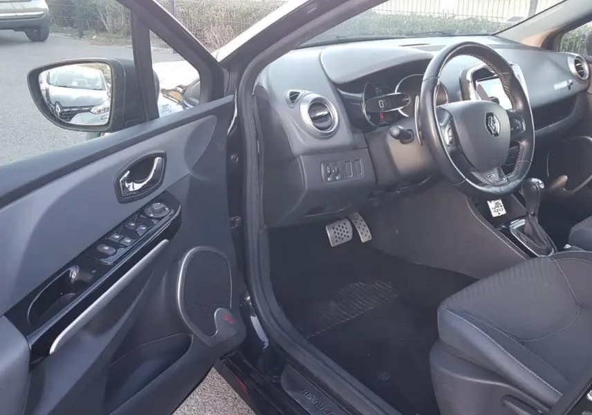 Intérieur côté conducteur d'une Renault Clio IV Estate noir, volant cuir et console avec boîte automatique visible.
