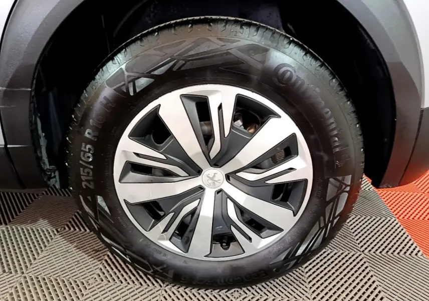 Gros plan sur la roue avant droite d’un Peugeot 2008 gris clair, avec jante alliage au design moderne.