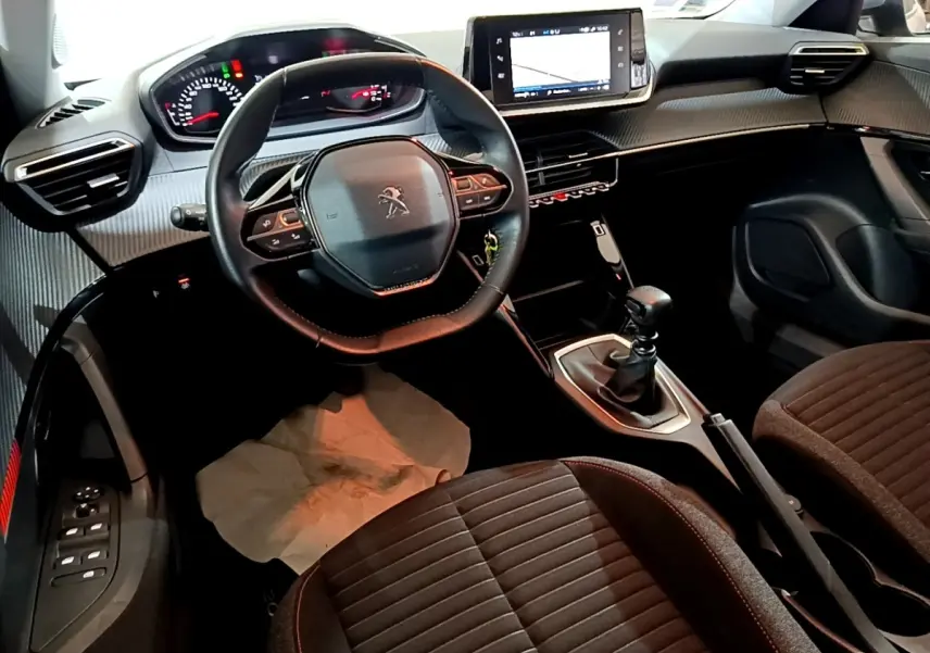 Vue intérieure avant du Peugeot 2008 gris clair, mettant en valeur le volant cuir multifonctions et l’écran tactile central.