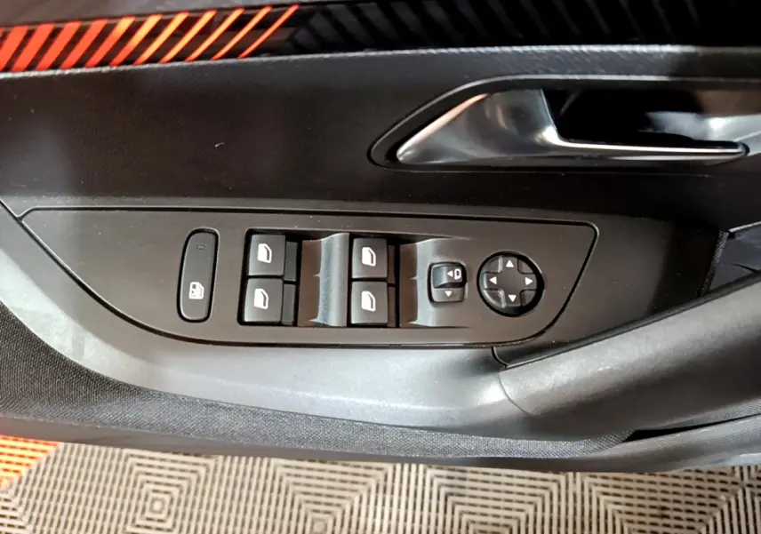 Vue rapprochée du panneau de commande des vitres et rétroviseurs côté conducteur d’un Peugeot 2008 gris clair.