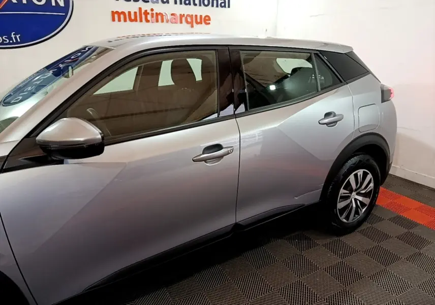 Vue latérale droite d'un Peugeot 2008 gris clair, mettant en valeur les lignes anguleuses et les jantes modernes.