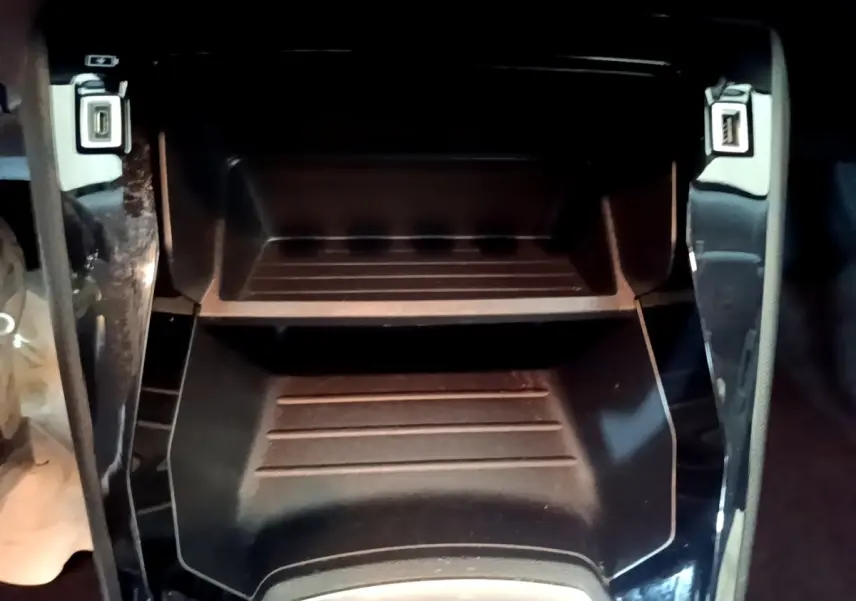 Gros plan sur le rangement central noir avec ports USB avant du Peugeot 2008 gris clair, version PureTech 100 S&S ACTIVE BUSINESS.