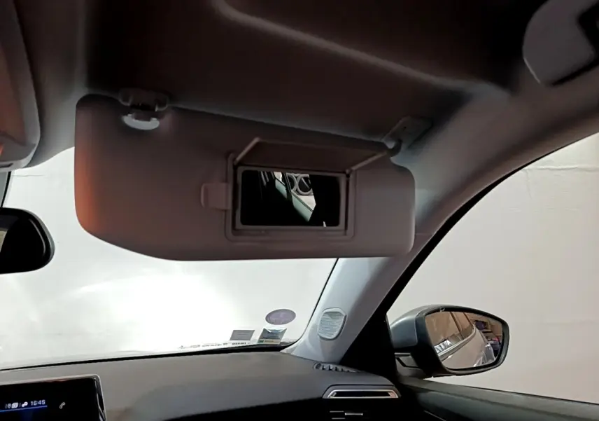 Vue intérieure côté conducteur du Peugeot 2008 gris clair 2021, avec pare-soleil déplié et rétroviseur latéral visible.