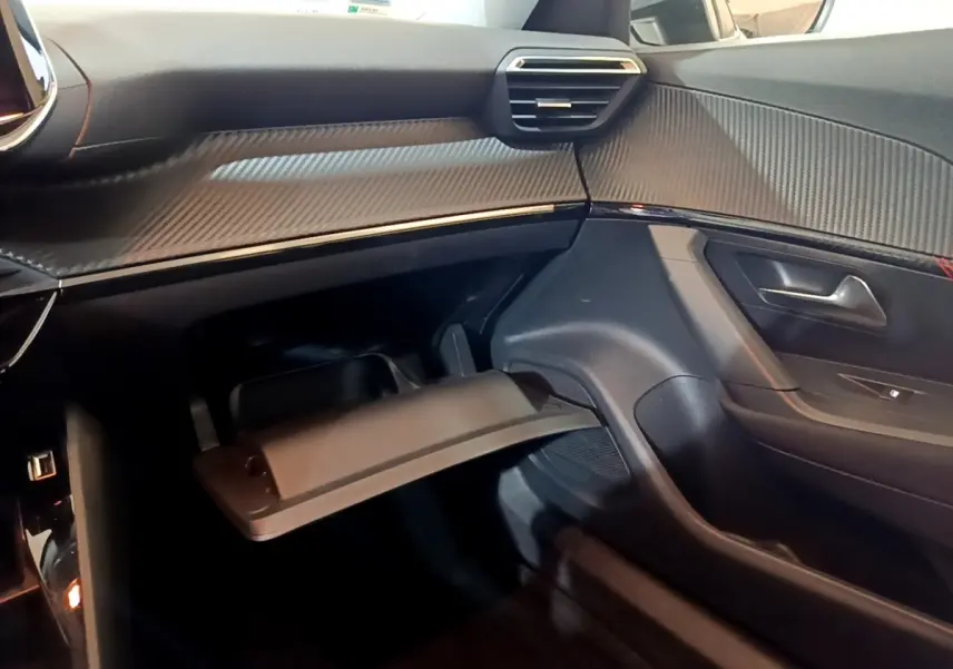 Intérieur du côté passager du Peugeot 2008 2021, tableau de bord avec finition carbone et boîte à gants ouverte.