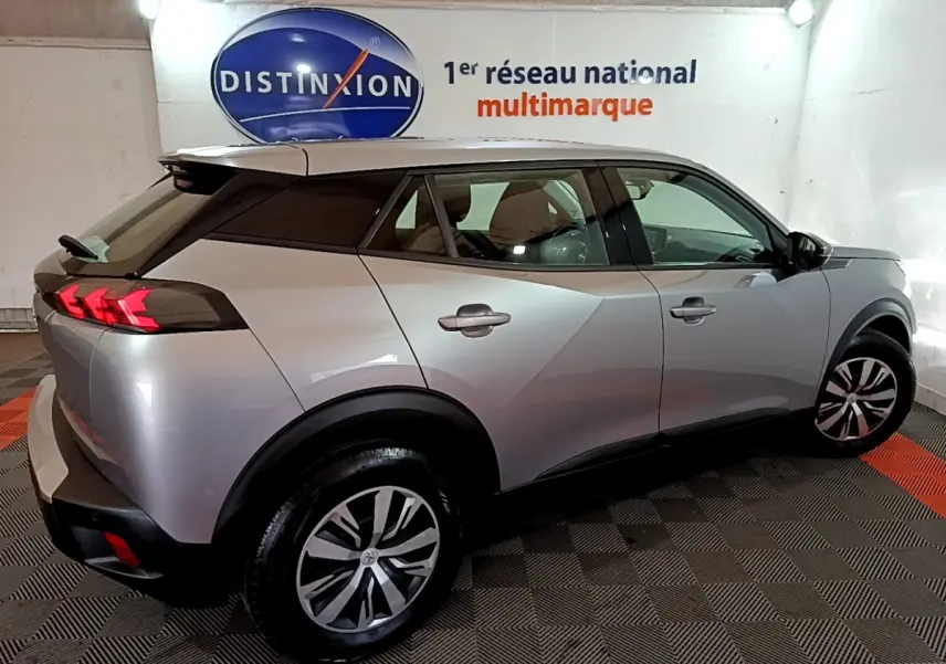 Vue 3/4 arrière droite d’un Peugeot 2008 gris clair avec feux arrière LED et jantes alliage dans un showroom.