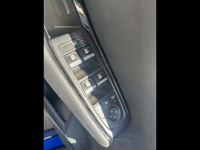 Gros plan sur les commandes de lève-vitres et rétroviseurs côté conducteur du Renault Austral bleu Iron.