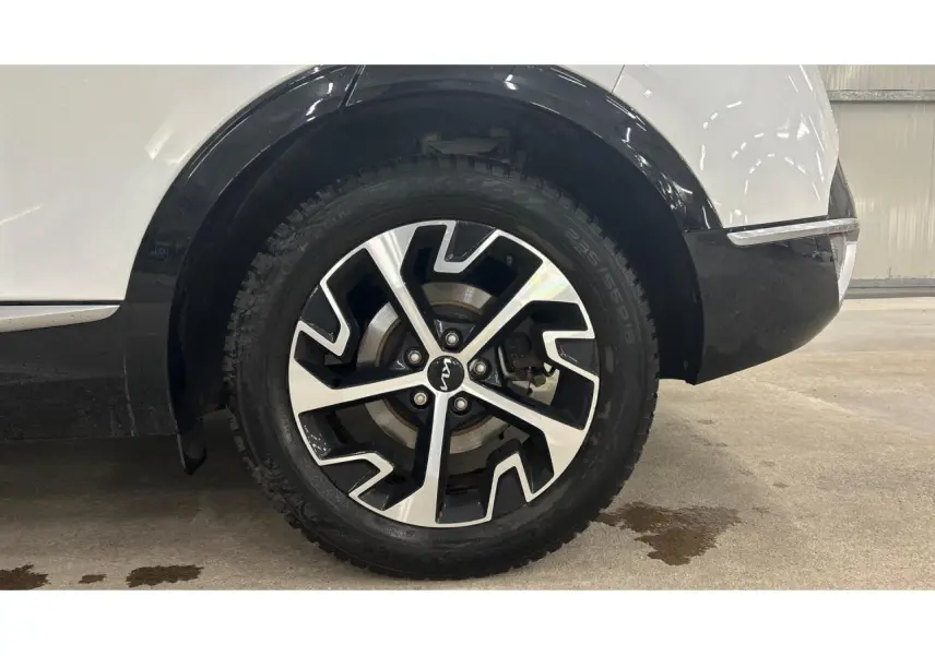 Gros plan sur la roue arrière droite du KIA SPORTAGE blanc avec jante alliage 18 pouces noir et argent.