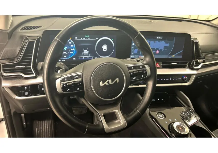 Vue intérieure centrée sur le volant cuir noir et le tableau de bord digital du Kia Sportage hybride 2022.