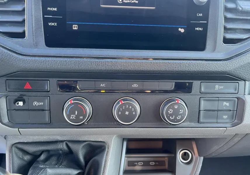 Tableau de bord du Volkswagen Crafter blanc 2022, vue rapprochée des commandes de climatisation et boîte manuelle.