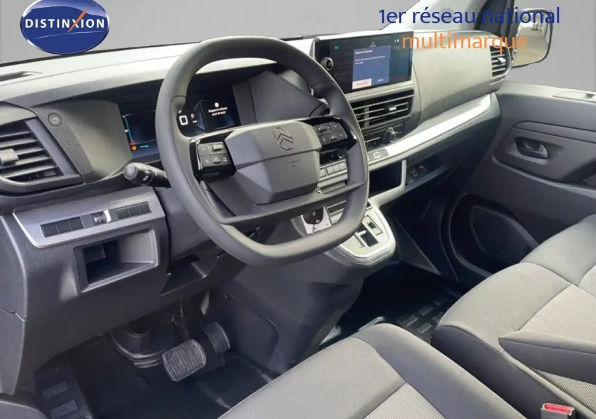 Vue intérieure côté conducteur du Citroën Jumpy gris titane, mettant en valeur le tableau de bord et le volant multifonction.