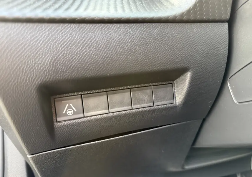 Gros plan sur les boutons de commande noirs du tableau de bord côté gauche du Peugeot 2008 Hybrid 145ch gris Selenium.