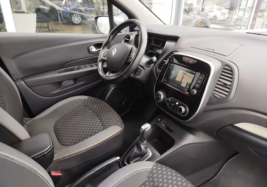 Vue intérieure côté conducteur du Renault Captur 2018, tableau de bord noir avec écran tactile et sellerie tissu gris.