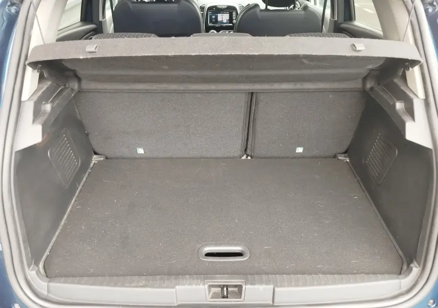 Coffre ouvert vu de l'arrière d'un Renault Captur bleu marine fumé avec intérieur gris et banquette arrière visible.