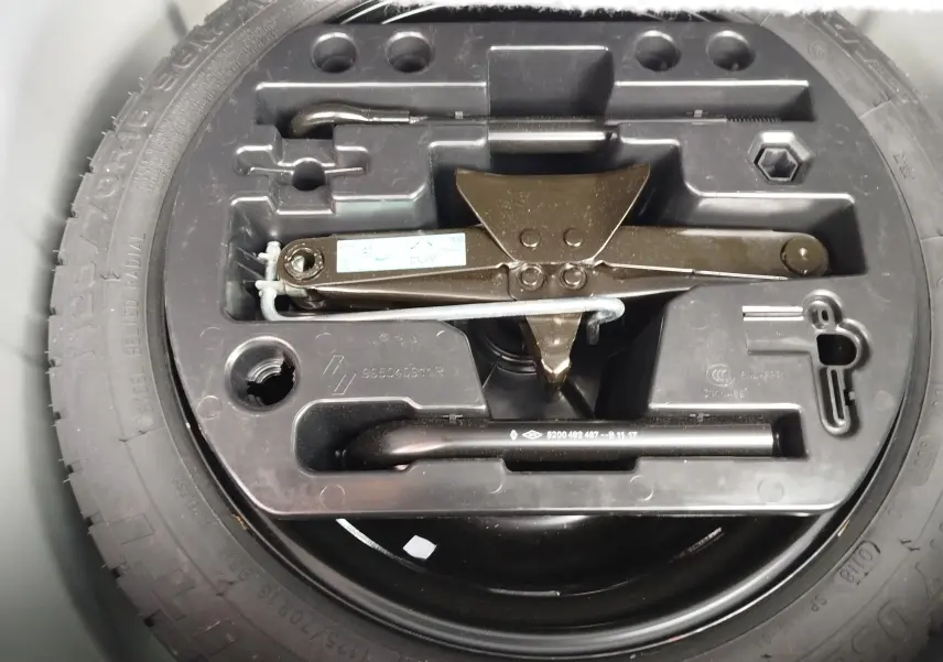 Vue rapprochée du coffre d’un Renault Captur 2018 montrant la roue de secours et le kit de changement de pneu intégré.