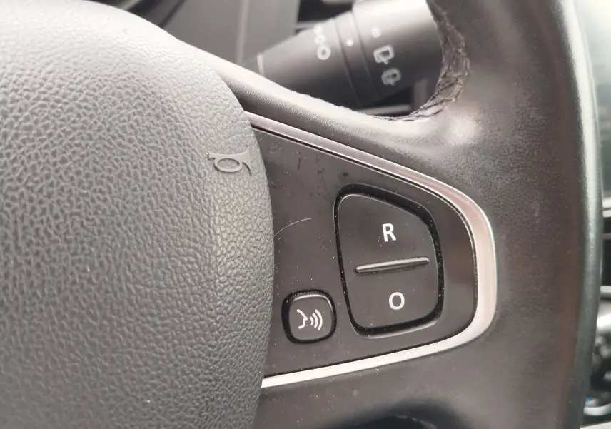Gros plan sur les commandes noires du volant en cuir noir du Renault Captur 2018, boutons R et O visibles.