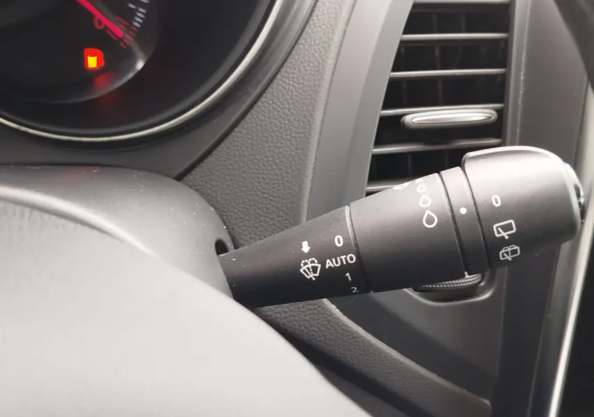 Gros plan sur la commande d’essuie-glace à droite du volant dans l’habitacle du Renault Captur 2018 bleu marine fumé.
