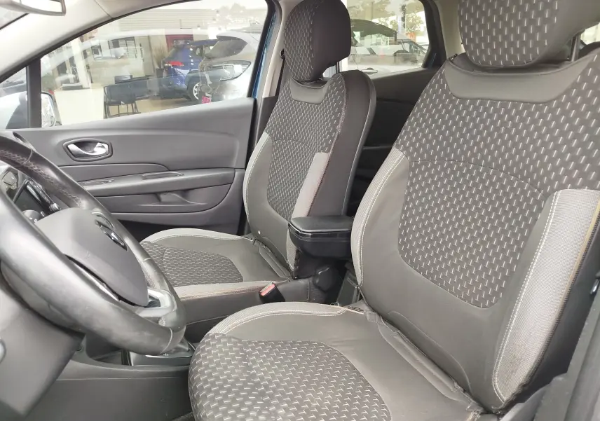 Vue intérieure côté conducteur du Renault Captur 2018, sièges tissu gris à motifs géométriques et accoudoir central.
