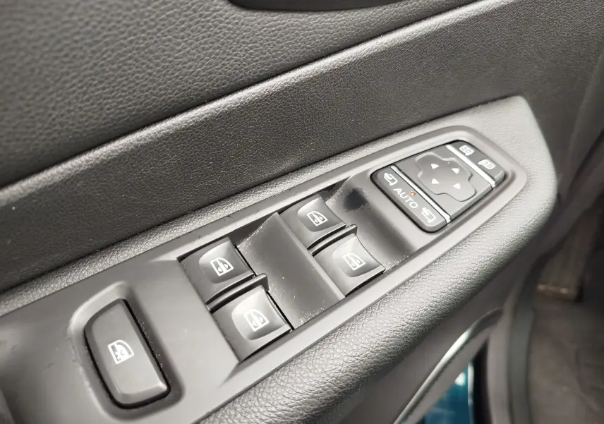 Gros plan sur les commandes des vitres électriques et rétroviseurs côté conducteur du Renault Captur bleu marine 2018.