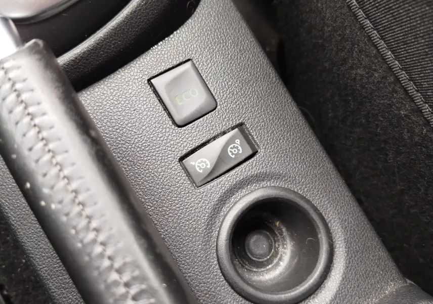 Gros plan sur les boutons de commande ECO et régulateur de vitesse dans la console centrale d’un Renault Captur bleu marine.