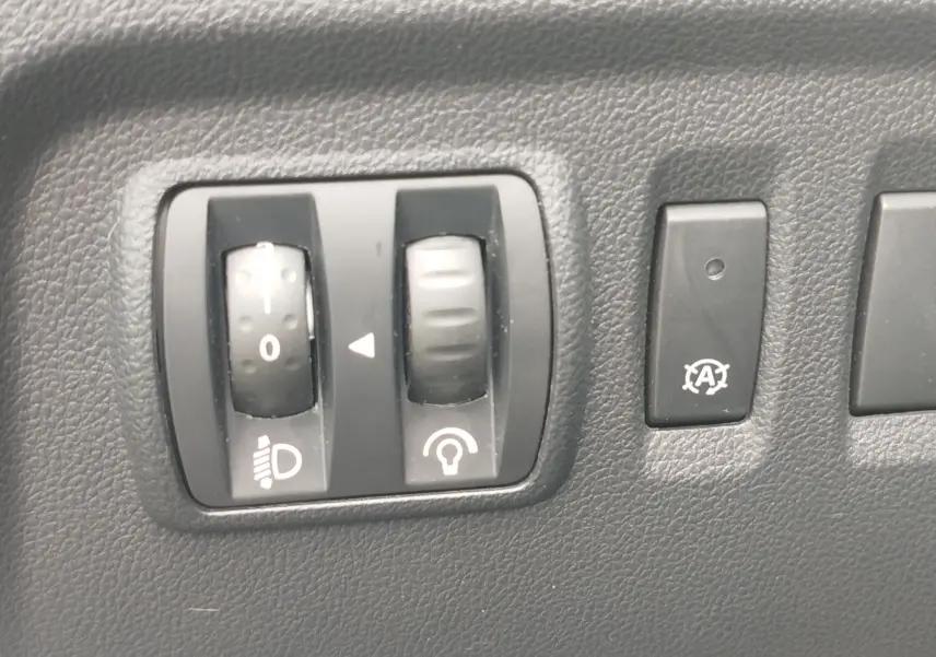 Gros plan sur les commandes de réglage des phares et de l'éclairage intérieur du Renault Captur bleu marine fumé 2018.