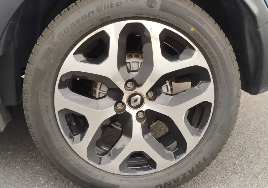 Gros plan sur la jante alliage bi-ton noir et argent d’un Renault Captur bleu marine fumé, roue avant droite.