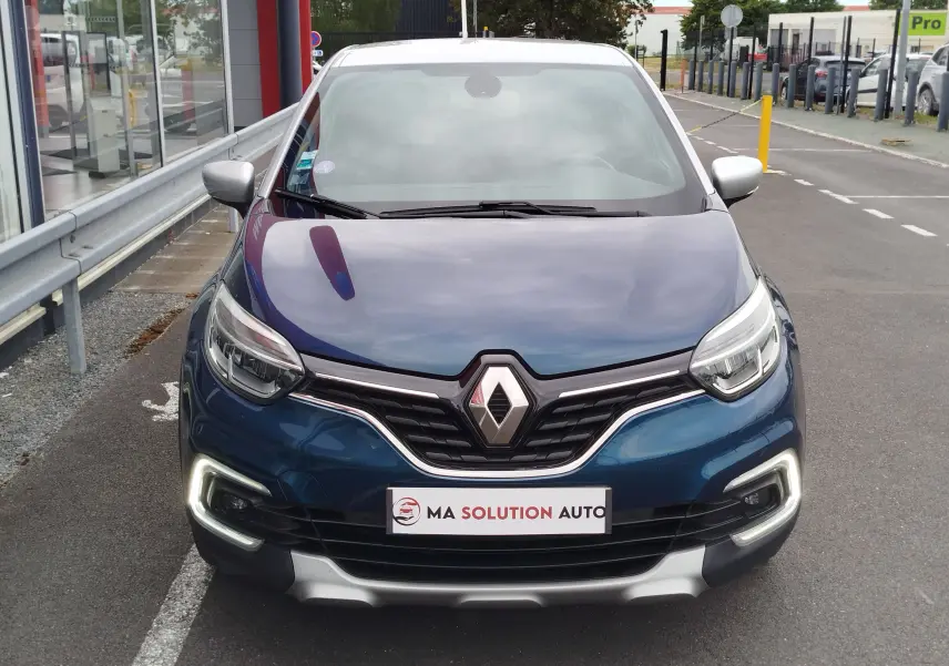 Vue avant d'un Renault Captur 2018 bleu marine fumé avec toit gris platine et feux LED allumés.