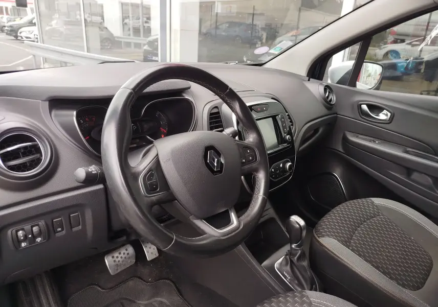 Vue intérieure côté conducteur du Renault Captur 2018, tableau de bord noir avec volant cuir et console centrale équipée.