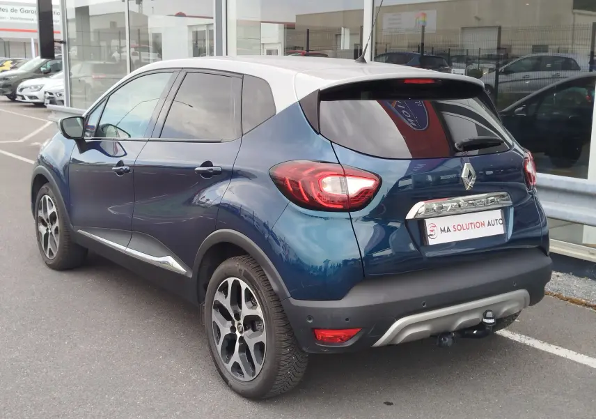 Vue 3/4 arrière droite d'un Renault Captur bleu marine fumé avec toit gris platine, jantes bi-ton et attelage visible.