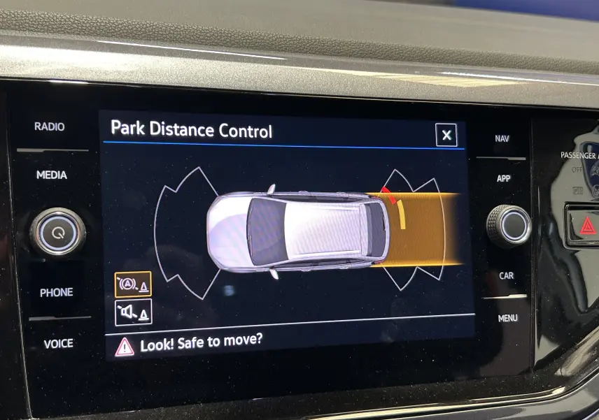 Écran intérieur du Volkswagen Taigo blanc montrant l'alerte de distance de stationnement arrière en mode automatique.