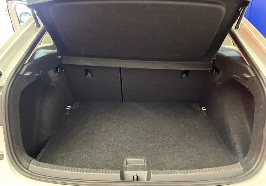 Coffre ouvert vu de l'arrière d'un Volkswagen Taigo blanc pur, montrant un espace de chargement propre et spacieux.