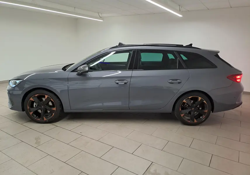 Vue de profil côté gauche d'une CUPRA Leon ST 2025 gris Graphène avec jantes cuivrées et toit ouvrant panoramique.