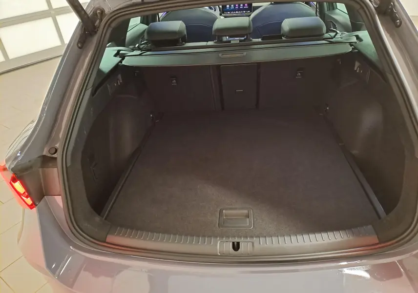 Coffre ouvert vu de l'arrière d'une CUPRA LEON ST 2025 gris Graphène, montrant un espace de chargement spacieux et propre.