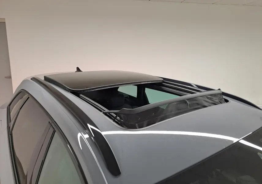 Vue en plongée du toit ouvrant panoramique ouvert sur la CUPRA LEON ST gris Graphène, avec barres de toit noires visibles.