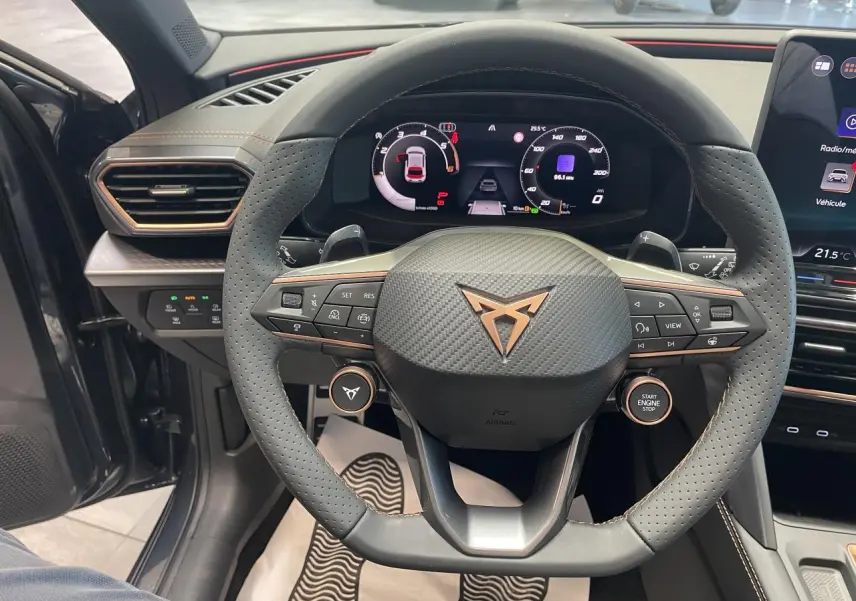 Vue intérieure centrée sur le volant perforé noir avec logo cuivré et tableau de bord digital de la CUPRA Leon 2026.