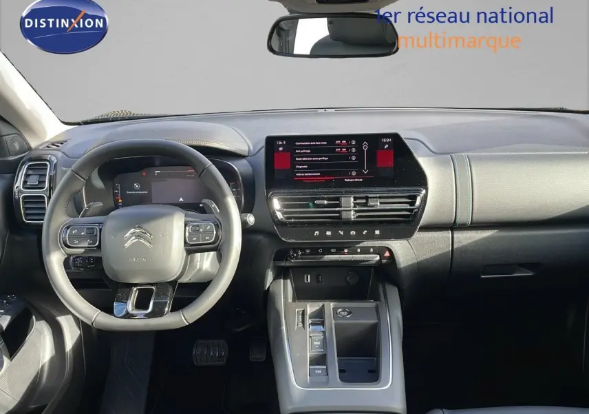 Vue intérieure frontale du tableau de bord et volant gris clair du Citroën C5 Aircross 2025 avec écran tactile central allumé.
